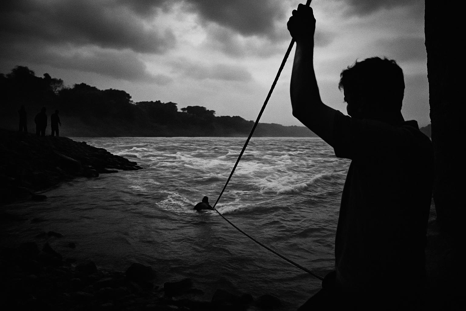 Grayscale editorial illustration: ઝરીયા ગામે ઝડપભર્યું રેસ્ક્યૂ, નદીકાંઠે કૌતુક નહીં એ જ જીવ બચાવતી નીતિ
